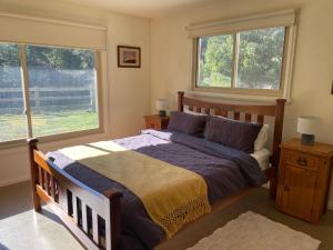 a bedroom with a wooden bed and two windows at One Mile Bridge - Off Grid Stays in Mole Creek