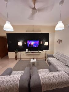 a living room with a couch and a flat screen tv at Electrifying 2BHK Gateways in Bengaluru +3 photos