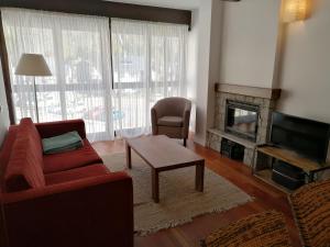 a living room with a red couch and a fireplace at Esterri Confort in Esterri d'Àneu +8 photos