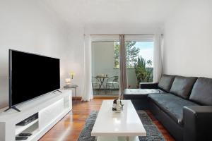 a living room with a black couch and a flat screen tv at Casa Nóbrega in Caniço