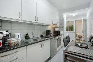 a white kitchen with white cabinets and a sink at Casa Nóbrega in Caniço