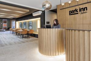 a woman standing at a counter in a park inn lobby at Park Inn by Radisson Melbourne Carlton in Melbourne +44 photos
