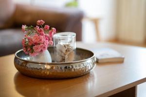 Un cuenco de metal con flores y conchas sobre una mesa en Ferienwohnung 1, en Todendorf auf Fehmarn