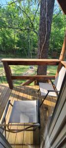 a wooden deck with a bench and a tree at Tree House Glamping Destination near the Ozarks, with River Access for Swimming and Fishing in West Liberty