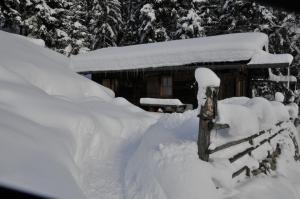 a fence covered in snow next to a cabin at Jägerhütte in Lutago