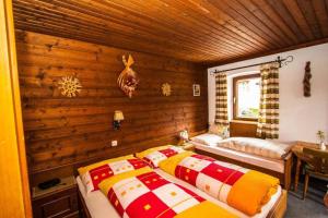 two beds in a room with wooden walls at Hinterauhof in Rain