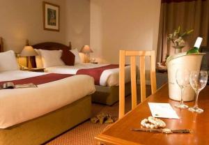 a hotel room with two beds and a table with wine glasses at Great National South Court Hotel in Limerick