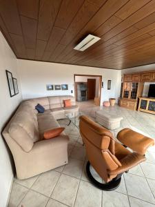 un soggiorno con un divano e una sedia di Ferienwohnung Hocheifelblick a Reifferscheid