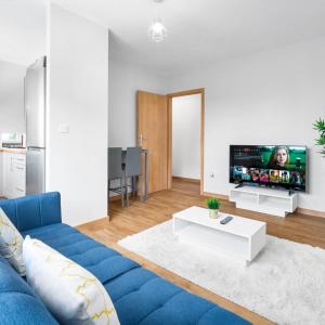 a living room with a blue couch and a tv at Stylish 2 Bedroom Apartment - Netflix - Off Street Parking 1DS in Amblecote