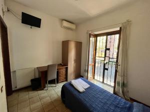 Un dormitorio con una cama y un escritorio y una ventana. en Domus Getsemani, en Roma