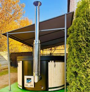 een barbecue onder een luifel in een tuin met een struik bij Apartament Sweet Garden in Huta Szklana