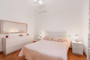 a white bedroom with a bed and a mirror at Villa Durán in Cantillana +18 photos