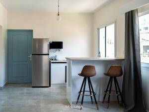 eine Küche mit Kühlschrank und zwei Barhockern in der Unterkunft Meluna in Mamoudzou