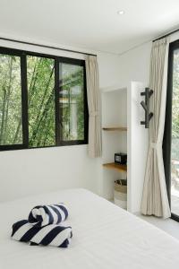 a white bedroom with a large bed and windows at Villas Tamu 1 in Bingin Beach