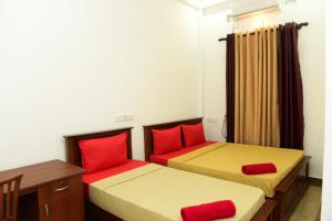 two beds with red pillows in a room at Royal Beach Hotel in Trincomalee