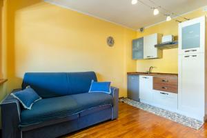 a living room with a blue couch and a kitchen at Hostdomus - City Center Apartment in Sestriere +8 photos