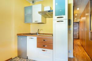 a kitchen with white cabinets and a sink at Hostdomus - City Center Apartment in Sestriere