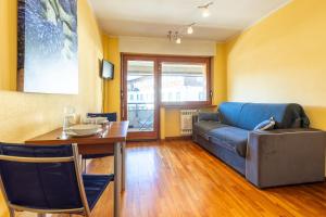 a living room with a couch and a table at Hostdomus - City Center Apartment in Sestriere
