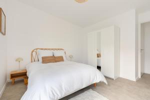 a white bedroom with a white bed and a table at Jolie maison de style bohème, douce et lumineuse in Bordeaux