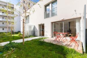 a garden with red chairs and a table on a wooden deck at Jolie maison de style bohème, douce et lumineuse in Bordeaux