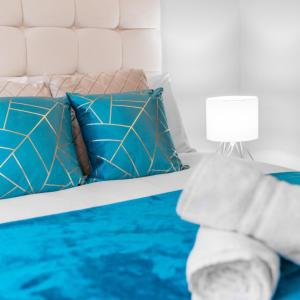 a bed with blue and white pillows and a lamp at Stylish 2 Bedroom Apartment - Netflix - Off Street Parking 1DS in Amblecote +29 photos
