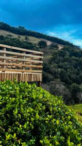 a wooden fence in front of a field of bushes at Chalé Rio Capetinga 01 in Anchieta
