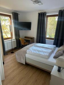 a bedroom with a bed and a desk and two windows at Pension Zollhaus in Oy-Mittelberg +10 photos