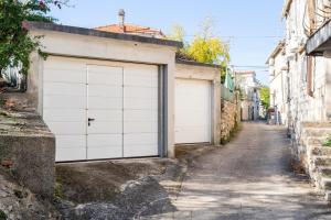 een steegje met twee witte garagedeuren aan een straat bij Villa Dororeja in Veliki Drvenik +38 foto's