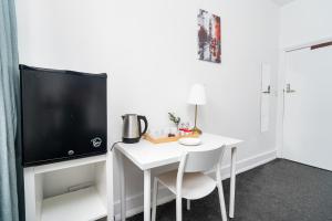 Russel Square Rooms في لندن: مكتب أبيض مع تلفزيون وطاولة وكراسي بيضاء