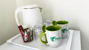 a shelf with two coffee mugs and a pitcher at The M GuestHouse in Kempton Park