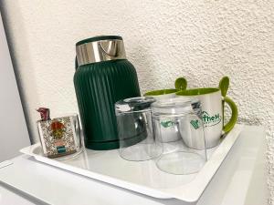 a shelf with cups and jars and a green thermos at The M GuestHouse in Kempton Park