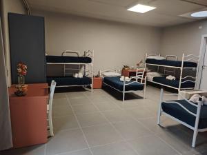a room with three bunk beds and a table and chairs at Batteria Chiodo rifugio escursionistico e culturale in Monte Marcello