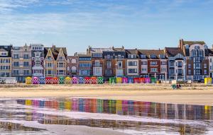 a group of colorful buildings on a beach with water at Cozy Apartment In Dunkerque in Dunkerque