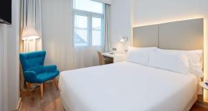 Un dormitorio con una cama blanca y una silla azul. en NH Bilbao Deusto, en Bilbao