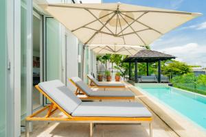 a row of lounge chairs and an umbrella next to a swimming pool at Surin Heights Villa in Surin Beach