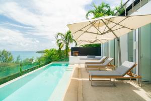 a swimming pool with lounge chairs and an umbrella at Surin Heights Villa in Surin Beach