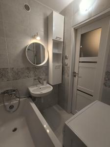 a bathroom with a sink and a tub and a mirror at Piotrków Trybunalski Comfort Apartment by BookingHost in Piotrków Trybunalski
