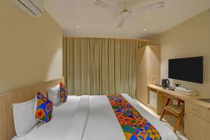a hotel room with a bed and a desk with a television at FabHotel Blue Moon in Hanamkonda