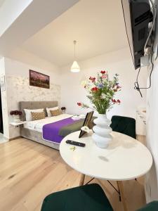 a bedroom with a bed and a table with flowers on it at Studios Palas by GLAM Center Area and Mall - Parking Option in Iaşi