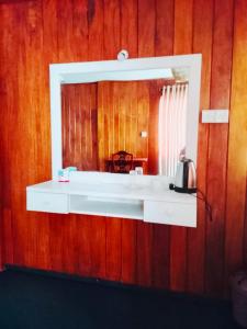 a mirror on a wooden wall with a sink at Why Not Guest house in Hikkaduwa