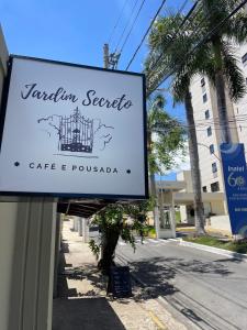 Un cartel de un café y poulada en una calle en Café e Pousada Jardim Secreto, en Santa Rita do Sapucaí
