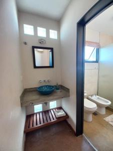 een badkamer met een wastafel, een toilet en een spiegel bij CuyenCo Casa de campo in Santa Rosa de Calamuchita +8 foto's