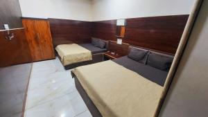Una habitación pequeña con dos camas y un faldón. en HOTEL OM NiWAS, en Ujjain