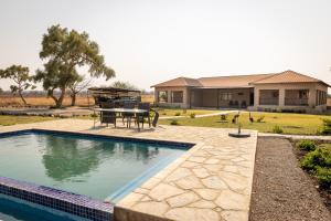 ein Pool mit Tisch und Grill neben einem Haus in der Unterkunft Rain Tree Camp in Chunga
