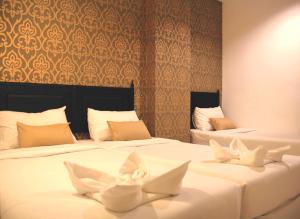 Duas camas com pássaros brancos num quarto em Erawan House em Bangkok