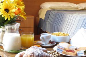 a table with breakfast foods and milk and a bed at Central Plaza Lecce in Lecce