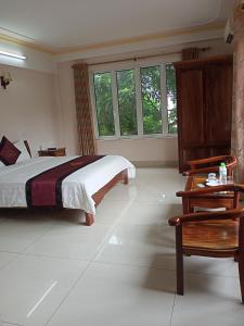 une chambre avec un lit, une table et des fenêtres dans l'établissement Khách Sạn Thành Loan 2, à Nà Phia