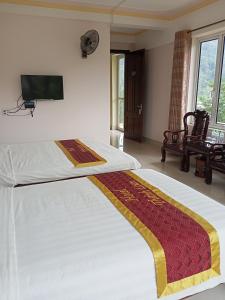 une chambre avec un lit et une télévision au mur dans l'établissement Khách Sạn Thành Loan 2, à Nà Phia