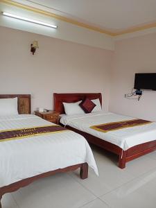 une chambre avec deux lits et une télévision au mur dans l'établissement Khách Sạn Thành Loan 2, à Nà Phia