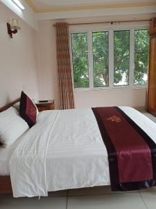 - une chambre avec un grand lit blanc et des fenêtres dans l'établissement Khách Sạn Thành Loan 2, à Nà Phia